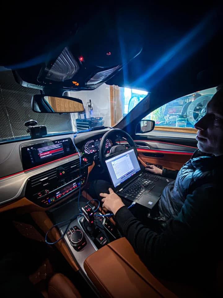 Technician remapping a BMW with a laptop connected inside the car
